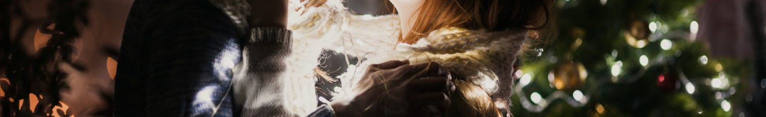 Ungt par kysser ved juletræ